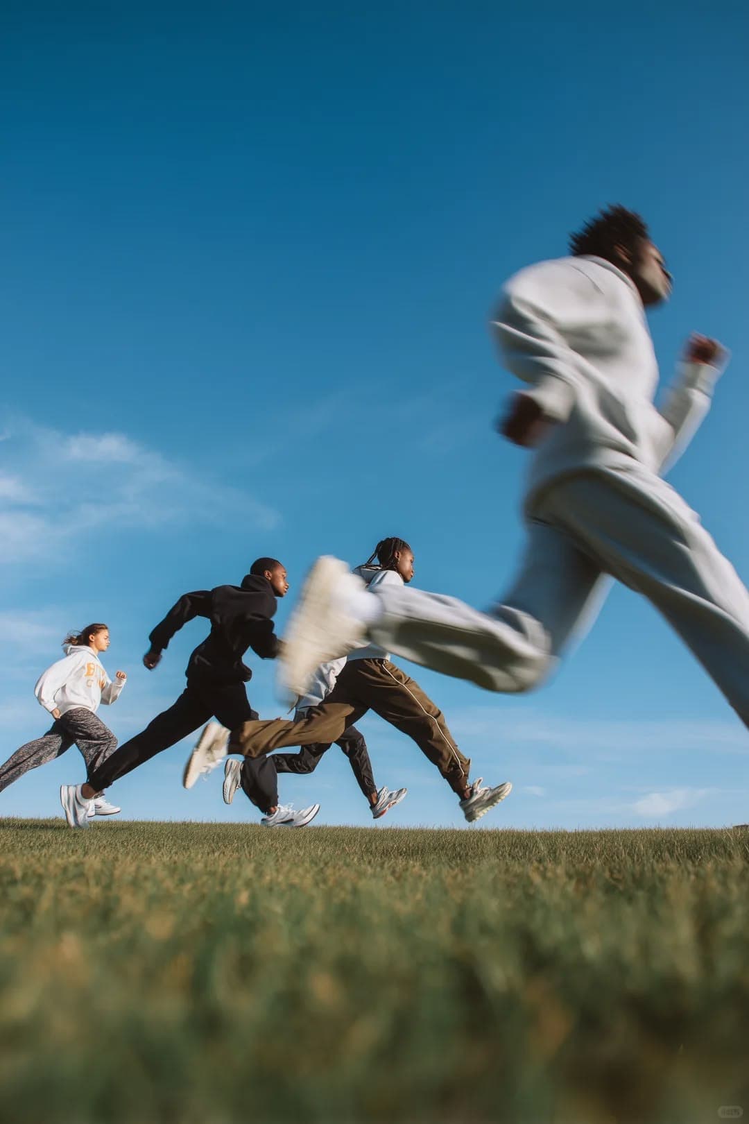Un grupo de personas corriendo por un prado bajo el cielo azul