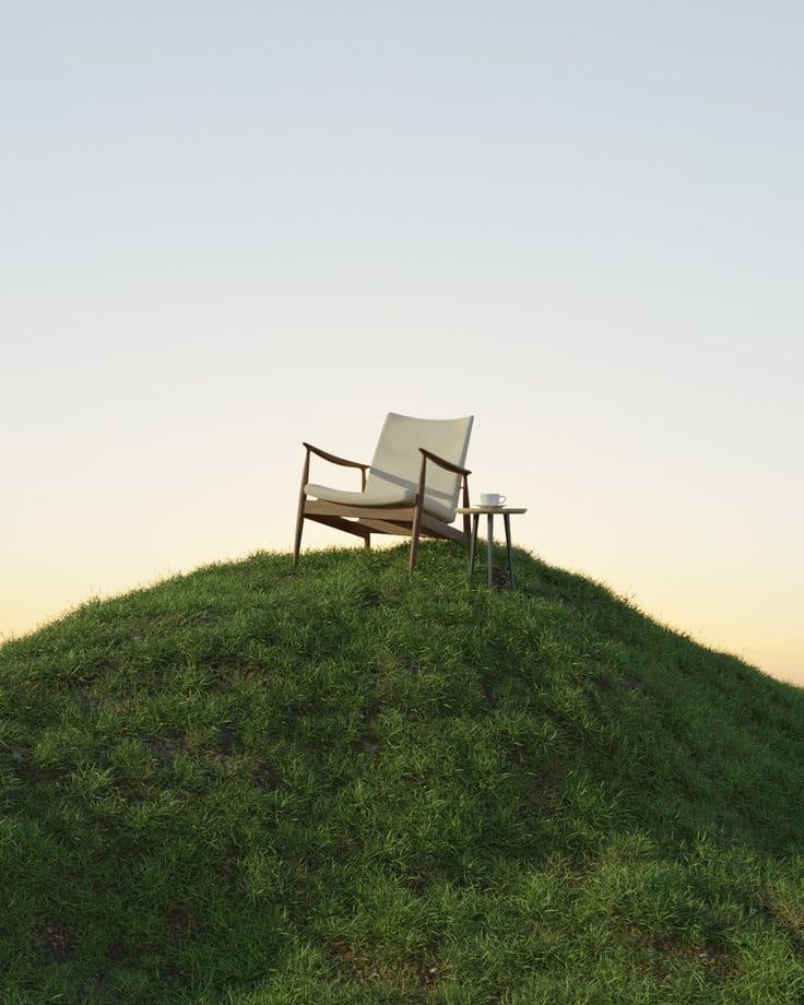 Un sillón solo en lo alto de una colina verde al atardecer